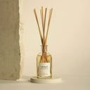 The Olphactory Eternal Sandalwood Noir geurstokjes op een lichte ronde sokkel